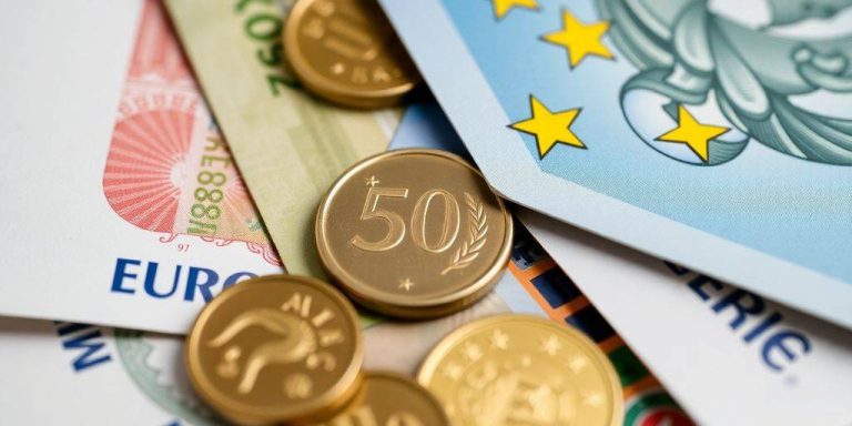 Euro banknotes and coins displayed in an artistic layout.