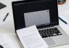 Workspace with laptop, financial documents, and a calculator.