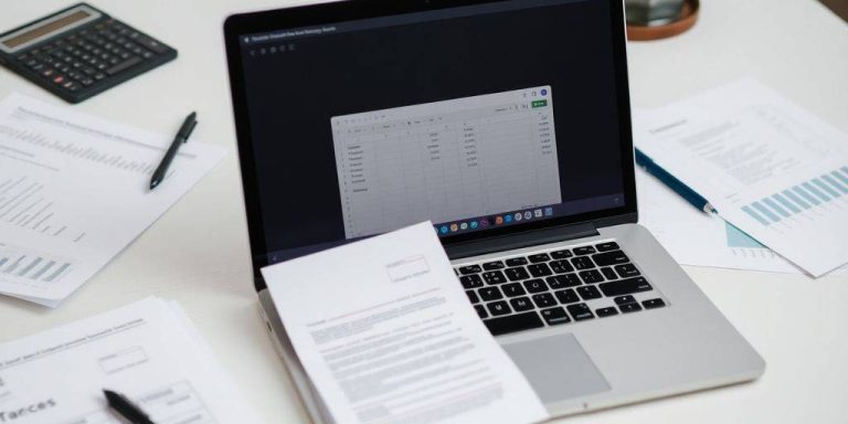 Workspace with laptop, financial documents, and a calculator.