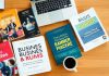 Flat lay of business books and workspace items.