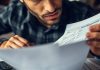Person analyzing finance documents with calculators and notebooks.
