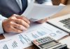 Business professional reviewing financial documents and calculator.
