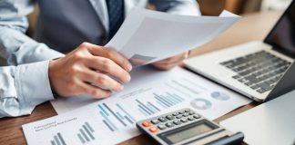 Business professional reviewing financial documents and calculator.