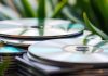 Stacked CDs with reflective surfaces and green backdrop.