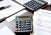 Calculator, notepad, and financial documents on a desk.