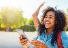 Person using smartphone outdoors, representing financial empowerment.