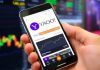 Person using Yahoo Finance app on smartphone outdoors.
