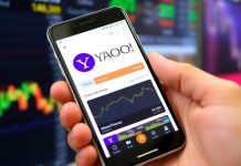 Person using Yahoo Finance app on smartphone outdoors.