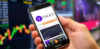 Person using Yahoo Finance app on smartphone outdoors.