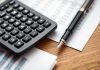 Calculator and documents on a desk for investment analysis.