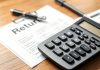 Calculator and financial papers on a wooden desk.