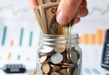 Hand placing cash in a jar for investment purposes.