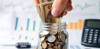 Hand placing cash in a jar for investment purposes.