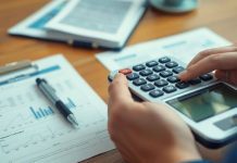 Person calculating investments with documents and calculator.