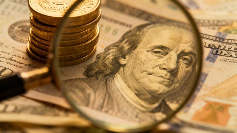 Financial terms explained with coins and magnifying glass.