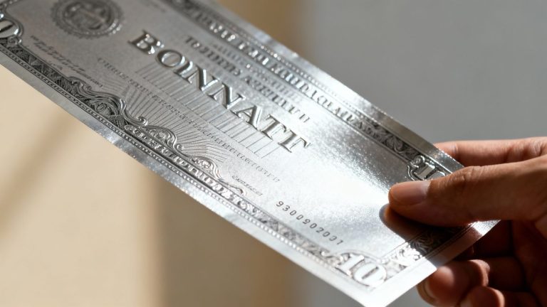 Silver bond certificate held in hand, financial document detail.