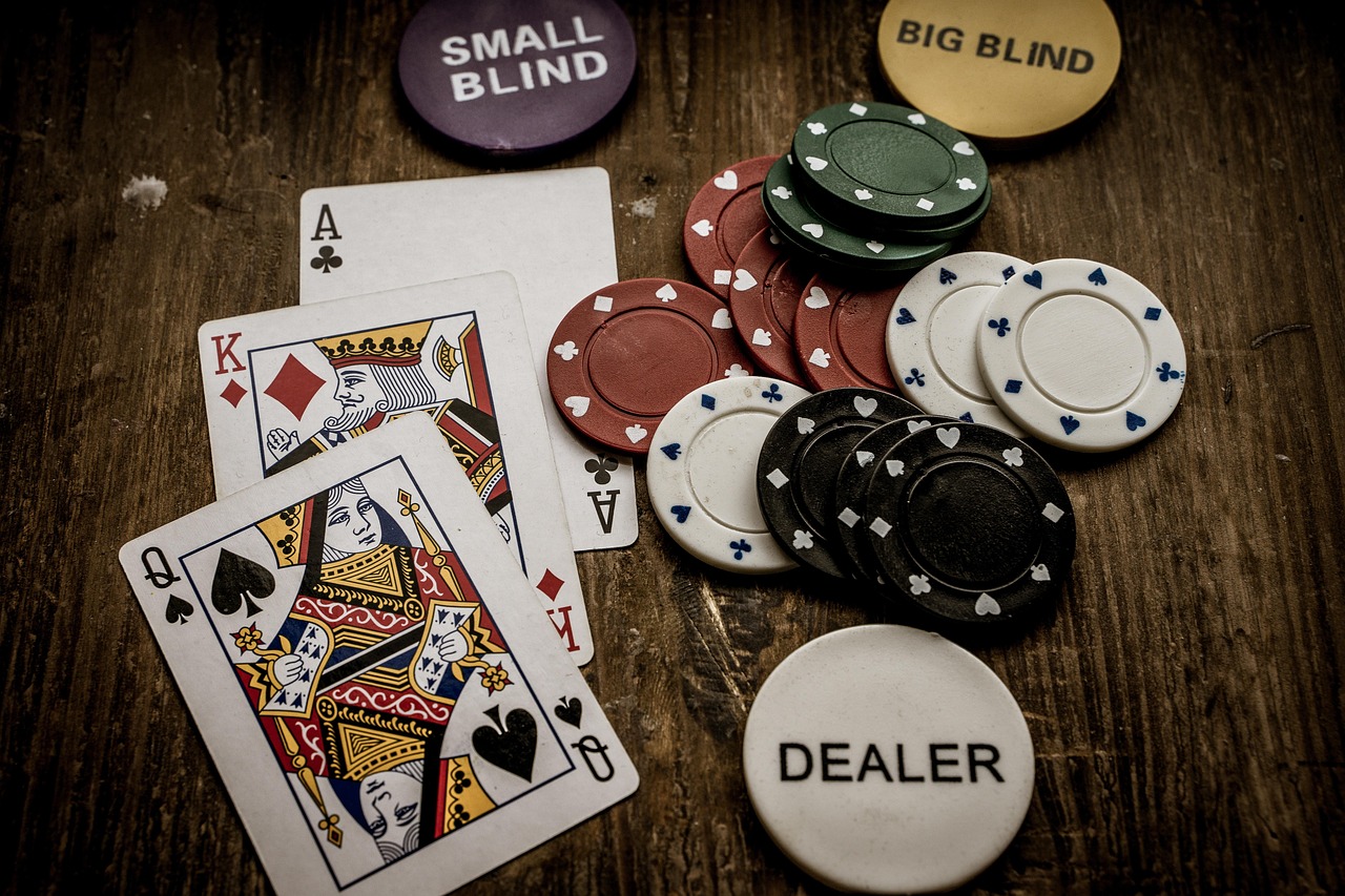 Photo of playing cards, poker chips, and dealer button on a wooden table